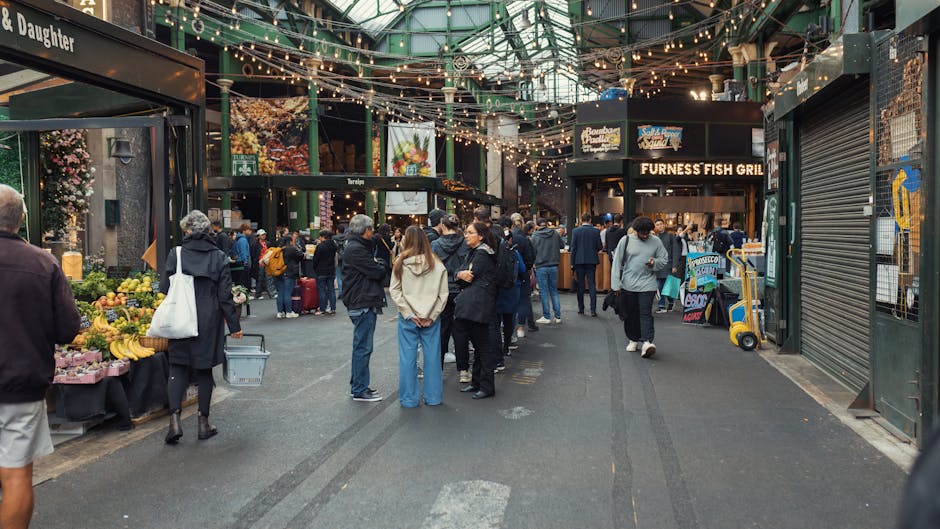 The image depicts an outdoor area under a large, curved, beige-colored roof structure supported by thick dark green metal columns. In the background, there is a red Mariah's Market food stall or kiosk